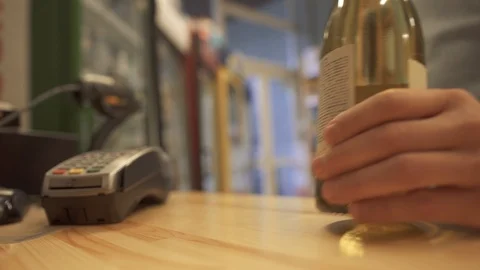 Guy paying with mobile phone contactless payment at liquor store. Seller counts Stock Footage 99374522
