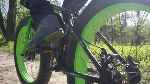 Guy pedals his electronic bicycle on a park trail, legs and wheels camera Stock Footage 75303642