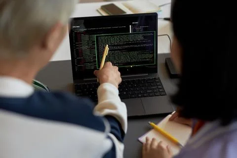 Guy with pen pointing at codes on laptop screen during presentation Stock Photos