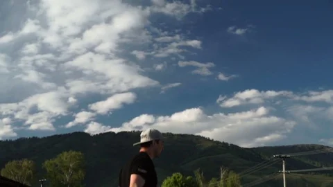 Guy performs acrobatic jumping on a trampoline against a background of mountains Stock Footage 77092163