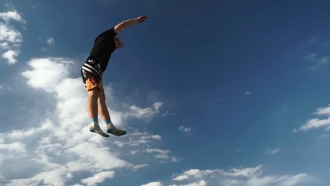 Guy performs acrobatic jumping on a trampoline against a background of mountains Stock Footage 77092186