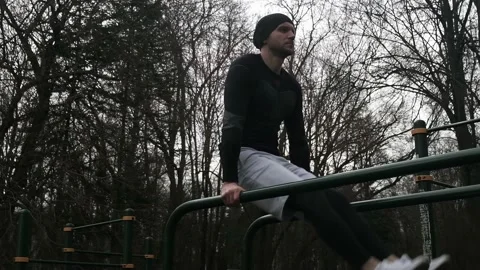 A guy performs an exercise to lift his legs on the uneven bars Stock Footage 237987624