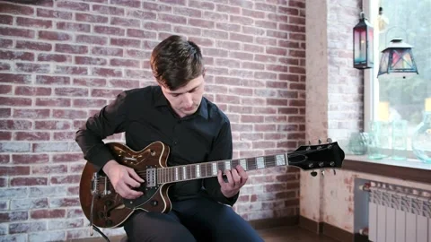 Guy performs jazz, blues music on guitar in bar. Retro studio, brick interior Stock Footage 135356305