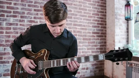 Guy performs jazz, blues music on guitar in bar. Retro studio, brick interior Stock Footage 135356331