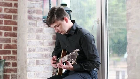 Guy performs jazz, blues music on guitar, sitting on windowsill in bar Stock Footage 135356620