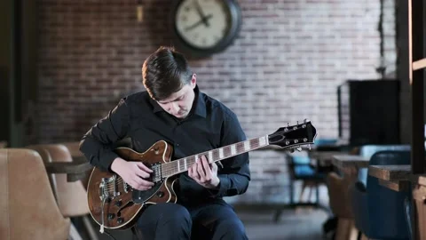 Guy performs jazz, blues music on guitar in bar. Retro studio, brick interior Stock Footage 135356661