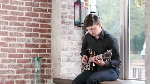 Guy performs jazz, blues music on guitar, sitting on windowsill in bar Stock Footage 135356985