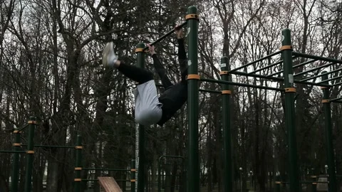 A guy performs a leg lift exercise on a horizontal bar Stock Footage 237987642