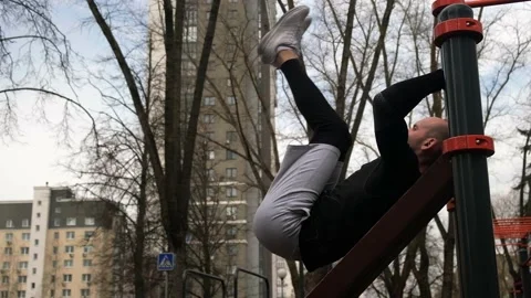 A guy performs a press exercise on a sports field on the street Stock Footage 237990676