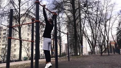 A guy performs a pull-up exercise on a horizontal bar on a sports Stock Footage 250969718