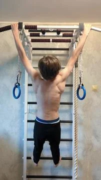 A guy performs a pull-up exercise on a horizontal bar at home Stock Photos