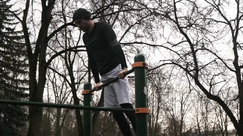 A guy performs a pull-up with a flip on a horizontal bar on a sports field Stock Footage 237988566