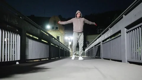 A guy performs resistance band exercises at night on a scenic bridge Stock Footage 310699729