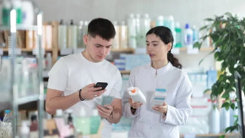 Guy in pharmacy scans QR code on emollient cream. Pharmacist offer help and Stock Footage 308958158