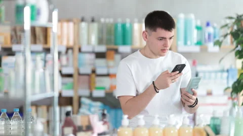 Guy in pharmacy scans QR code on emollient cream Stock Footage 312628652