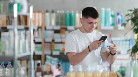 Guy in pharmacy scans QR code on antifungal ointment Stock Footage 317138623