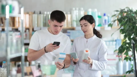 Guy in pharmacy scans QR code on emollient cream. Pharmacist offer help and Stock Footage 317533366