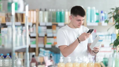 Guy in pharmacy scans QR code on emollient cream Stock Footage 323908406