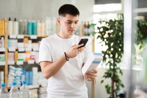 Guy in pharmacy scans QR code on emollient cream Foto stock