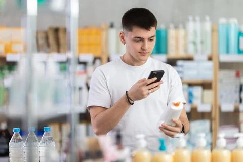 Guy in pharmacy scans QR code on emollient cream Fotos de archivo