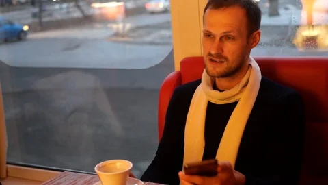 The guy with the phone is drinking coffee and talking with someone 動画素材 102545861