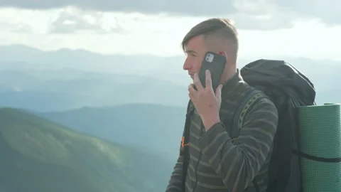 A guy with a phone while hiking in the mountains makes a call. Call friends Stock Footage 218441471