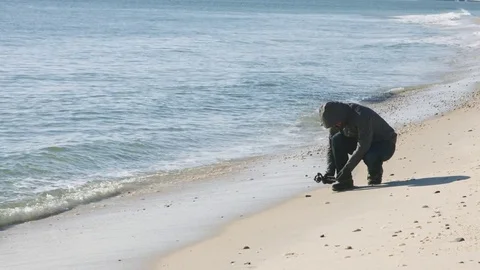 Guy picking up shells on ocean beach front Video stock 75169100