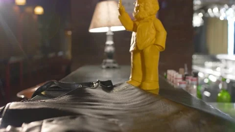 The guy picks up a dark leather apron from bar table. The figure of the gnome. Stock Footage 136155227