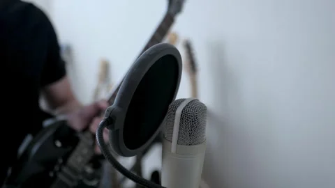 The guy picks up a guitar and sings into the studio microphone 库存影片 243443604