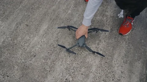 The guy picks up the quadcopter from the concrete floor after the flight Stock Footage 155211639