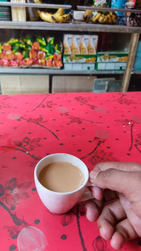 A guy piking up a small cup of milk tea from a red table in a tea stall Stock Footage 171417049