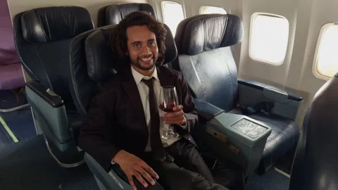 Guy on plane sips wine while chatting with smile Stock Footage 301440108