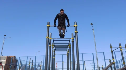 Guy playground, makes a coup on the horizontal bar street in sunny weather, body Vidéo 126929883