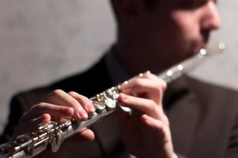 The guy is playing the flute. Close-up. Shallow depth of field. The hands of  Stock Photos
