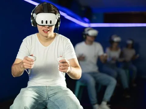 Guy playing game in virtual reality glasses in front of friends Stock Photos