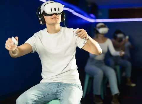Guy playing game in virtual reality glasses in front of friends Stock Photos