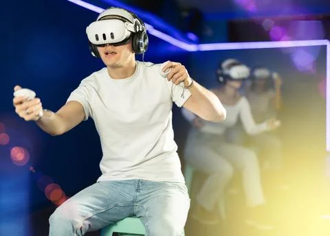 Guy playing game in virtual reality glasses in front of friends Stock Photos