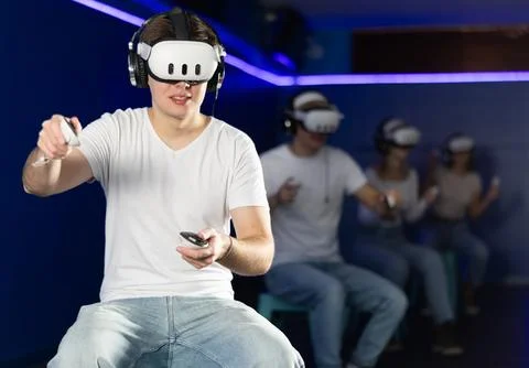 Guy playing game in virtual reality glasses in front of friends Stock Photos