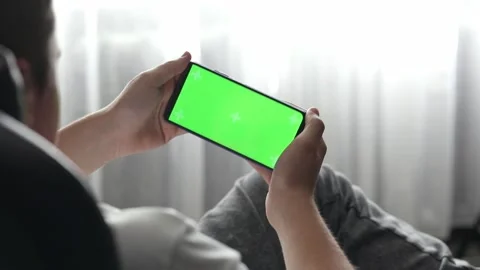 Guy playing green screen phone at home Stock Footage 194393365