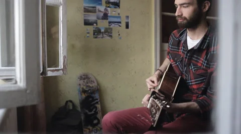 The guy playing the guitar and writing songs at home 動画素材 65220950