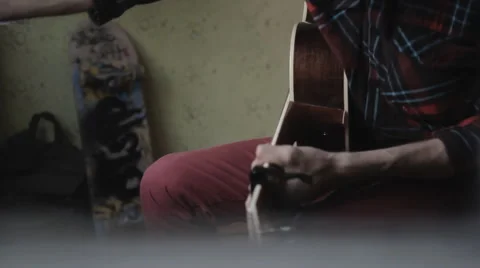 The guy playing the guitar and writing songs at home Stock Footage