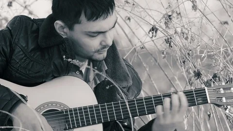 The guy playing the guitar in nature (b&amp;w) Stock Footage 73996569