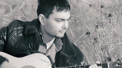 The guy playing the guitar in nature (b&amp;w) Stock Footage 73997594