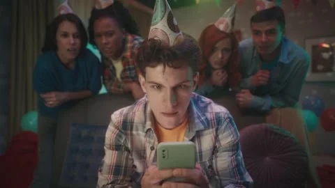 A guy is playing an online game on his phone, his friends are watching him Stock Footage 242112115