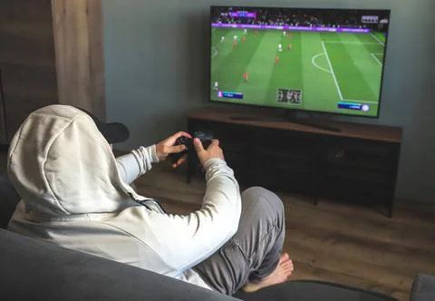 Guy playing a video game console. Game is football. Back view Stock Photos