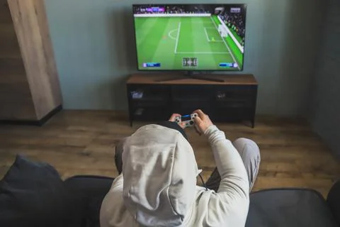 Guy playing a video game console. Game is football. Back view Stock Photos