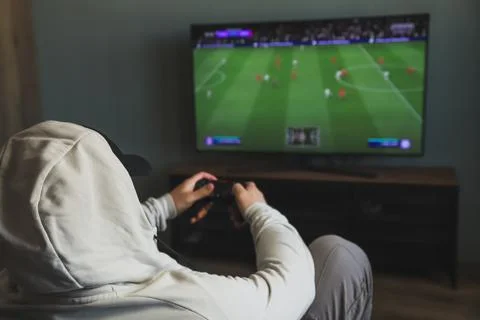 Guy playing a video game console. Game is football. Back view Stock Photos