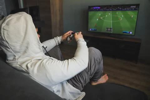 Guy playing a video game console. Game is football. Back view Stock Photos