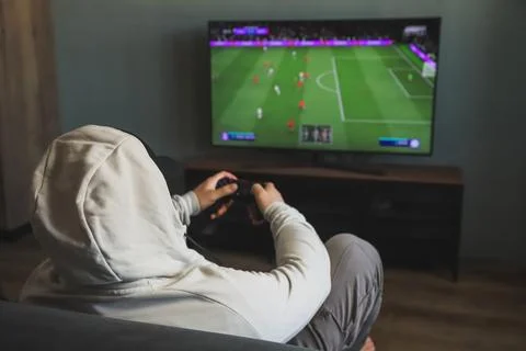 Guy playing a video game console. Game is football. Back view Stock Photos