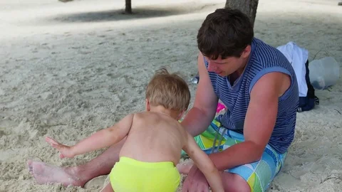 A guy plays with a child on the beach 스톡 동영상 75239993